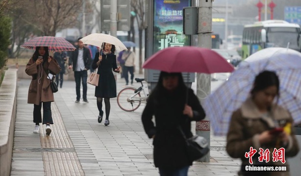 北京迎来降雨降温天气 市民雨中出行 第1页